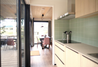 Cocina moderna y comedor en Timber Lodge 4, Gulpen, Países Bajos, con terraza y grandes ventanales.