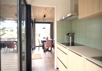 Moderne køkken og spisestue i Timber Lodge 4, Gulpen, Holland, med store vinduer og udendørs terrasse.