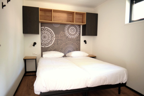 Kamer met twee eenpersoonsbedden, moderne muurdecoratie en kasten in Timber Lodge 4 te Gulpen, Nederland.