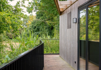 Balcón de Timber Lodge 4 con revestimiento de madera, barandilla negra y vista a la naturaleza.