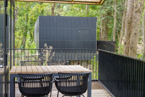 Houten terras met tafel en stoelen bij Timber Lodge 4 in Gulpen, Nederland, omringd door bomen.