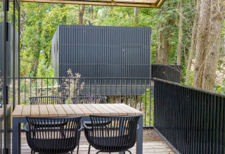 Houten terras met tafel en stoelen bij Timber Lodge 4 in Gulpen, Nederland, omringd door bomen.