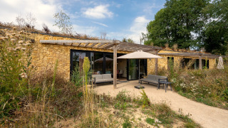 Buitenaanzicht van de Hillside Comfort 4 lodge met stenen muren, terras en natuurlijke begroeiing.