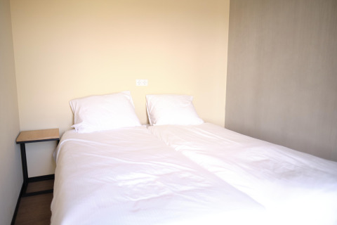 Et minimalistisk soveværelse på Hillside Comfort 4-lodgen i Gulpen, Nederlandene med to enkeltsenge.