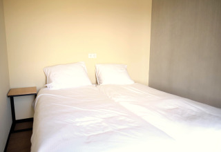 Et minimalistisk soveværelse på Hillside Comfort 4-lodgen i Gulpen, Nederlandene med to enkeltsenge.