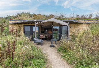 Außenansicht der Hillside Royal 4-Lodge mit begrünter Terrasse und Wildblumen rund um das Gebäude.