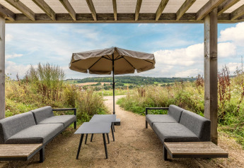 Buiten zithoek bij Hillside Royal 4 in Gulpen, Nederland, met parasol en uitzicht op het landschap.