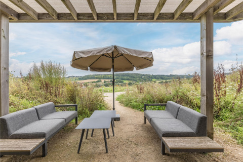 Zona de estar exterior en Hillside Royal 4 en Gulpen, Países Bajos, con sombrilla y vistas al paisaje.