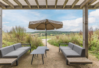 Zona de estar exterior en Hillside Royal 4 en Gulpen, Países Bajos, con sombrilla y vistas al paisaje.