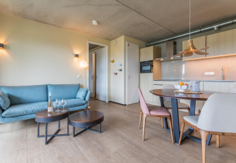 Sala moderna en lodge con sofá azul, mesa de comedor y cocina en Hillside Royal 4 en Gulpen, Países Bajos.