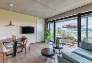 Luminoso y moderno salón en la cabaña Hillside Royal 4 en Gulpen, Países Bajos, con vistas a la terraza y campo.
