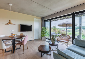 Luminoso y moderno salón en la cabaña Hillside Royal 4 en Gulpen, Países Bajos, con vistas a la terraza y campo.
