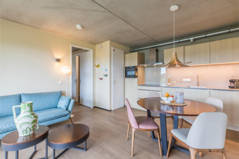 Zona giorno e cucina moderne al lodge Hillside Royal 4 a Gulpen, Paesi Bassi, con tavolo da pranzo elegante.