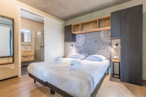 Dormitorio moderno con cama doble, pared decorada y baño en suite en Hillside Royal 4, Gulpen.