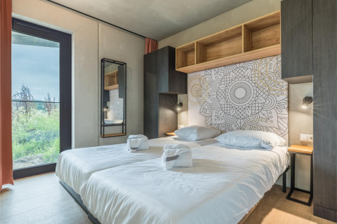 Dormitorio moderno con dos camas individuales, arte en la pared y gran ventana en Hillside Royal 4, Gulpen, Países Bajos.