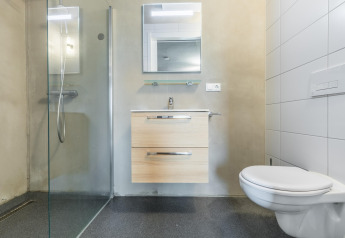 Baño moderno en la cabaña Hillside Royal 4 en Gulpen, Países Bajos, con ducha, lavabo y sanitario suspendido.