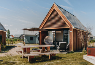 Moderne Tiny House 2 ved Nieuwvliet-Bad, Holland, med træfacade, havebord og terrasse under himlen.