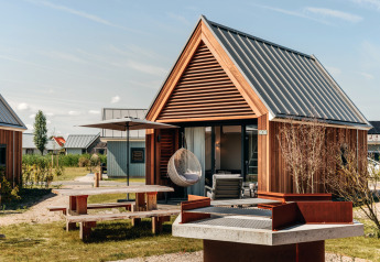Tiny House 2 à Nieuwvliet-Bad, Pays-Bas, avec bardage bois, coin salon et espace barbecue extérieur.