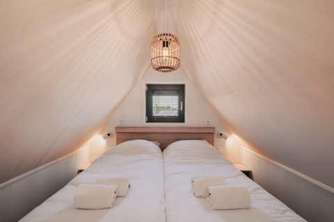 Bedroom with two single beds in Tiny House 2, Nieuwvliet-Bad, Netherlands. Cozy attic space and window.