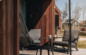 Gemütlicher Sitzbereich vor Tiny House 2 in Nieuwvliet-Bad, Niederlande, mit Stühlen auf Holzterrasse.