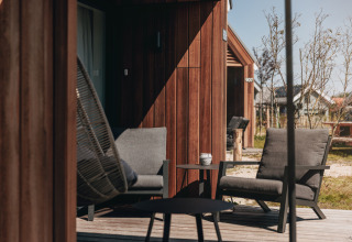 Outdoor seating at Tiny House 2 in Nieuwvliet-Bad, Netherlands, featuring modern chairs and wooden siding.