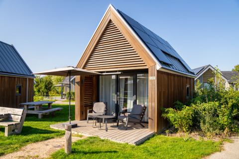 Tiny House 2 in Nieuwvliet-Bad, Niederlande, mit Holzfassade, Solarpaneelen und gemütlicher Veranda.