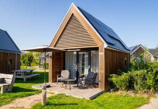 Billede af Tiny House 2 ved Nieuwvliet-Bad, Holland, med træfacade, solpaneler og udendørs siddeplads.