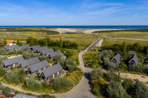 Aerial view of Nieuwvliet-Bad holiday park in Zeeland, Netherlands, featuring cabins by the sea and dunes.