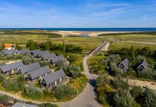 Luftfoto af feriepark i Nieuwvliet-Bad, Zeeland, Nederlandene, med hytter nær stranden og havet.
