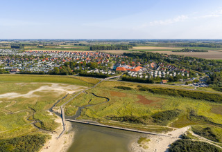 Luftfoto af ferieparken Nieuwvliet-Bad i Zeeland, Holland, omgivet af grønne marker og strand.