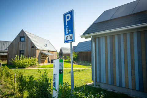 Electric car charging station and parking sign at holiday park cottages in Nieuwvliet-Bad, Zeeland, Netherlands.