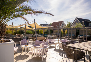 Udendørs terrasse med komfortable siddepladser og parasoller i Nieuwvliet-Bad feriepark, Zeeland, Holland.