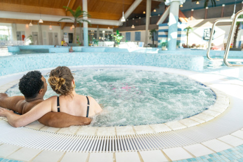 Paar entspannt sich gemeinsam im Whirlpool eines Ferienparks in Nieuwvliet-Bad, Zeeland, Niederlande.