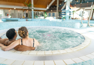 Couple relaxing in a hot tub at a holiday park in Nieuwvliet-Bad, Zeeland, Netherlands, enjoying leisure time.
