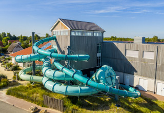 Große, gewundene Wasserrutsche am Ferienpark Nieuwvliet-Bad in Zeeland, Niederlande, neben modernen Gebäuden.