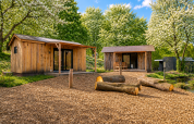 Deux cabanes en bois entourées d’arbres en fleurs au Nature House «Barn» à Camping Si-Es-An, Pays-Bas.