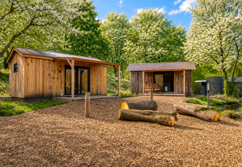 Deux cabanes en bois entourées d’arbres en fleurs au Nature House «Barn» à Camping Si-Es-An, Pays-Bas.