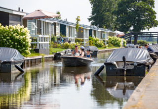 Både sejler gennem kanaler i ferieparken Giethoorn, omgivet af blomster og feriehuse i Overijssel, Holland.