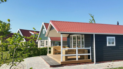 Cabaña grupal con techo rojo en Holiday park Eigen Wijze en los Países Bajos, rodeada de vegetación.