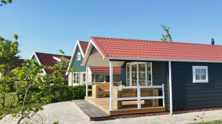 Cabaña grupal con techo rojo en Holiday park Eigen Wijze en los Países Bajos, rodeada de vegetación.