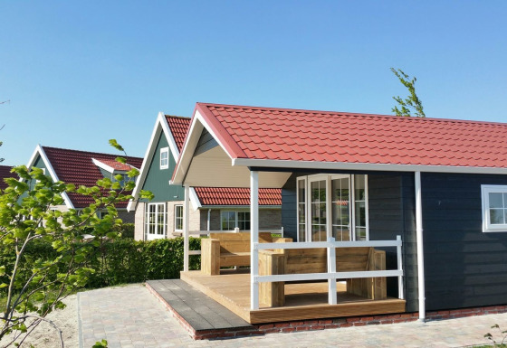 Cabaña grupal con techo rojo en Holiday park Eigen Wijze en los Países Bajos, rodeada de vegetación.
