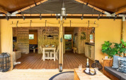 Vista interior de la tienda safari Dreamer en Petite Suisse, Bélgica, con terraza de madera y sofá acogedor.