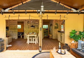 Interno della tenda safari Dreamer presso Petite Suisse in Belgio con veranda in legno e area relax accogliente.