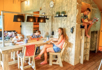 Famiglia che si rilassa nella tenda safari Dreamer a Petite Suisse, Belgio, in un ambiente accogliente.