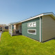 Moderne lodge Fuut 4 in Giethoorn, Nederland, met groen gazon aan de gracht en boten onder een blauwe lucht.