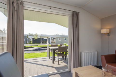 Udsigt fra stue i Meerkoet 4 lodge i Giethoorn, Holland med terrassebord og grøn udsigt.