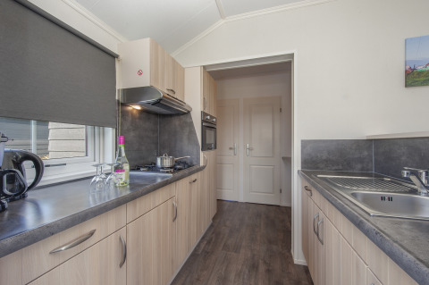 Moderne Küche in der Stern 6 Lodge in Giethoorn, Niederlande, mit Holzschränken, Herd und Fenster.