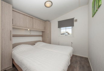 Bedroom in Stern 6 lodge in Giethoorn, Netherlands, featuring a double bed, wooden cabinets, and window.