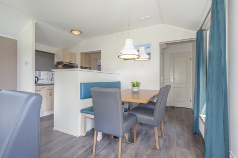 Essbereich in der Lodge Stern 6 in Giethoorn, Niederlande, mit blauem Sofa, Holztisch und Hängelampen.