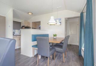 Essbereich in der Lodge Stern 6 in Giethoorn, Niederlande, mit blauem Sofa, Holztisch und Hängelampen.